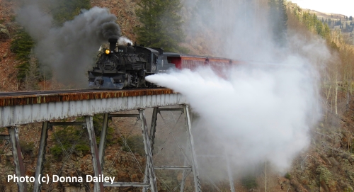 Train blowing steam and crossing a bridge on the Cumbres and Toltec Scenic Railroad in Colorado and New Mexico