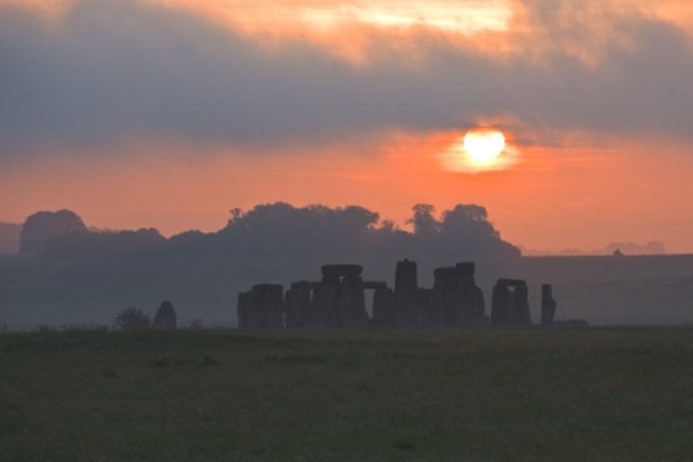 The sun rises behind the famous landmark of Stonehenge.